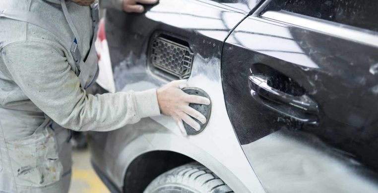 Car painter preparing car for painting in workshop. Car painter preparing car for painting in workshop.